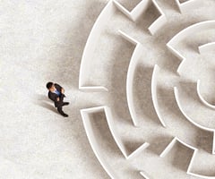 Business person about to enter a maze, looking for help
