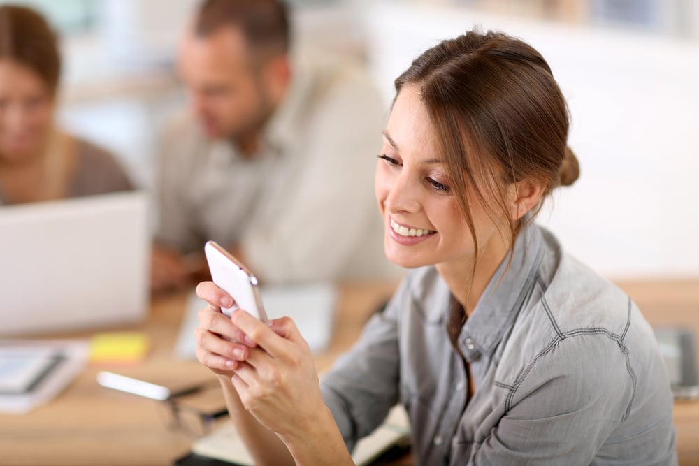 Young woman in training class sending text message