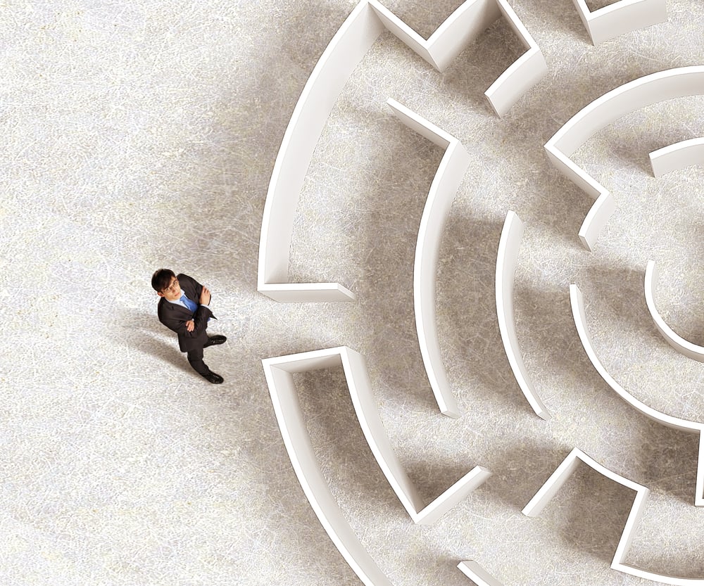 Business person about to enter a maze, looking for help